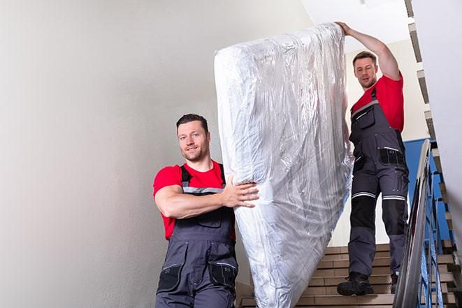 bedroom clutter being cleared as workers remove box spring in Brooklyn Center